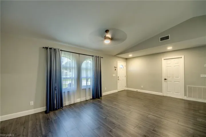Foyer entrance featuring a ceiling fan, lofted ceiling, dark wood-style floors, and baseboards