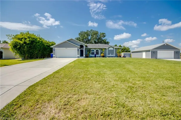 Ranch-style home with a garage, concrete driveway, and a front yard