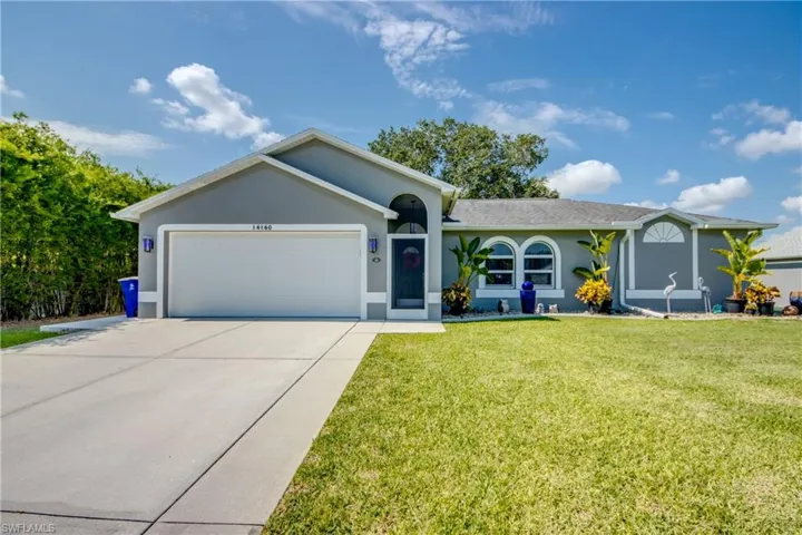 Ranch-style home featuring an attached garage, driveway, a front lawn, and stucco siding