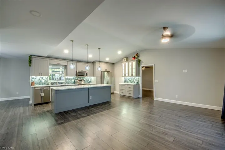 Kitchen featuring appliances with stainless steel finishes, decorative backsplash, ceiling fan, a kitchen island, and light countertops