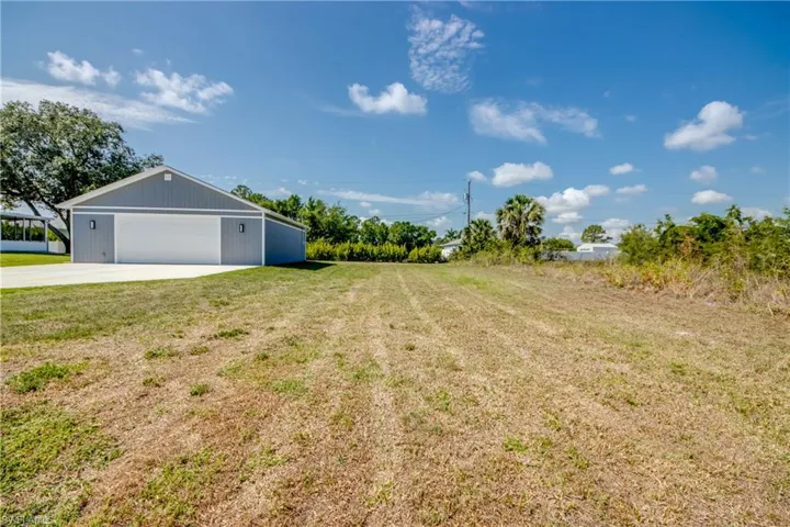 View of grassy yard with driveway and a detached garage