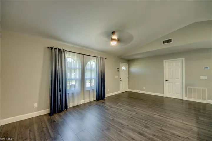 Foyer entrance with ceiling fan, lofted ceiling, dark wood-style flooring, and baseboards