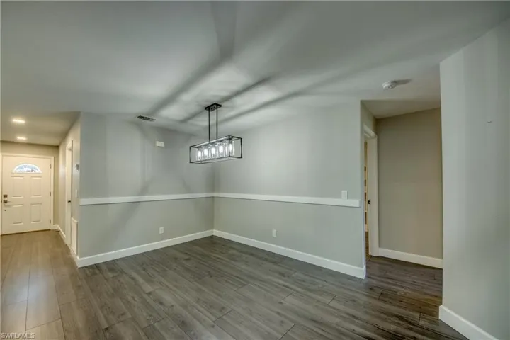 Unfurnished dining area with dark wood-style floors and baseboards