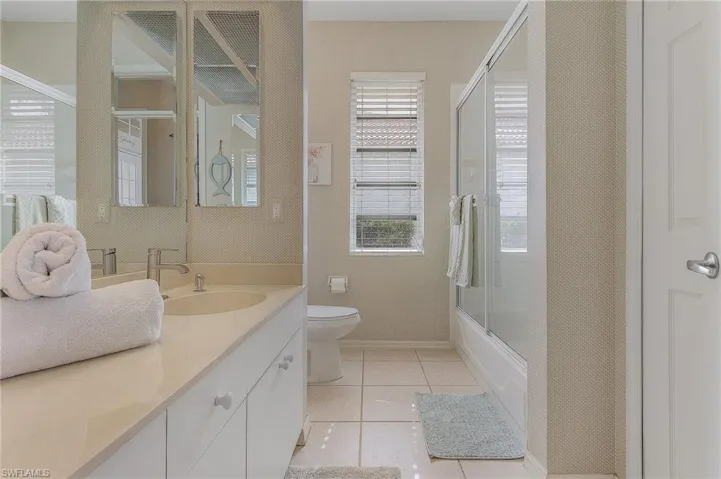 Full bathroom with tile patterned flooring, vanity, and enclosed tub / shower combo