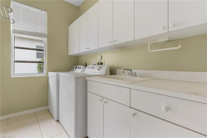 Washroom featuring cabinet space, washing machine and clothes dryer, and light tile patterned floors
