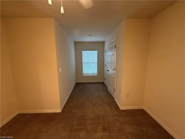 Hall featuring dark carpet and baseboards