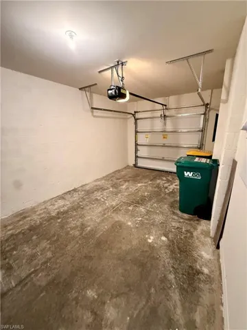 Garage featuring concrete block wall and a garage door opener