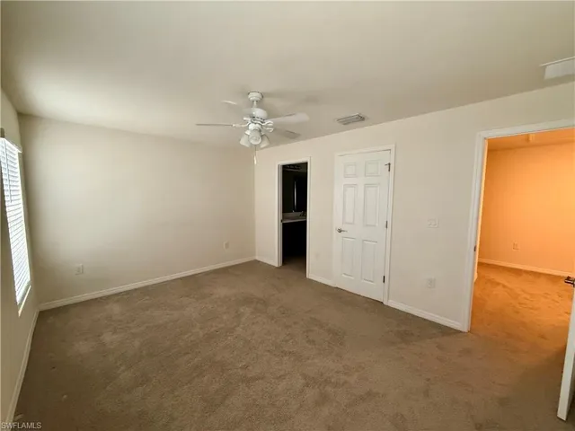 Unfurnished bedroom with carpet flooring, a ceiling fan, and ensuite bath