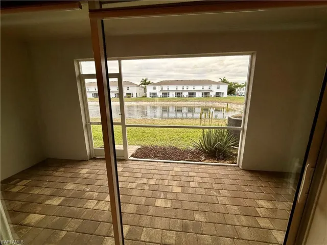 Doorway with brick patterned floors, a water view, and a residential view