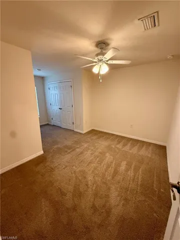 Carpeted spare room featuring baseboards and a ceiling fan