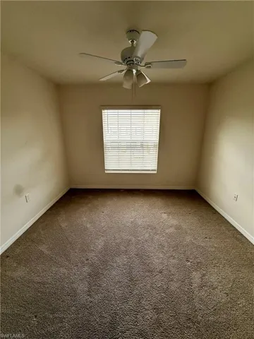 Carpeted spare room featuring baseboards and ceiling fan