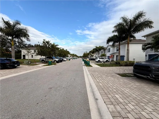 View of asphalt road with a residential view, sidewalks, and curbs