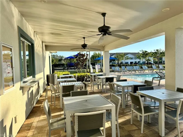 View of patio featuring outdoor dining space, a community pool, and ceiling fan