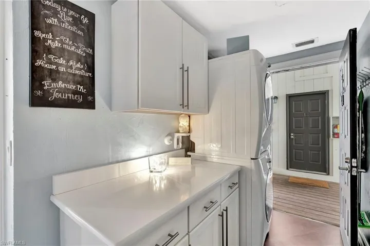 Laundry (stackable Electrolux washer/dryer) with built-ins, quartz countertops & a separate back door entry.