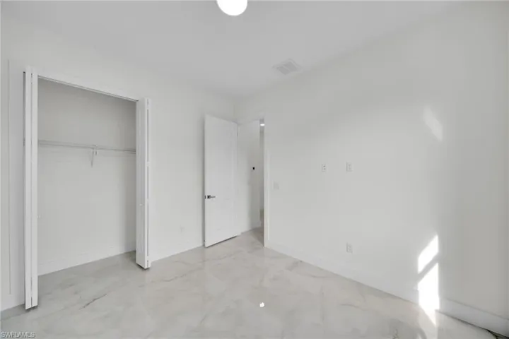 Unfurnished bedroom with light marble finish flooring and a closet