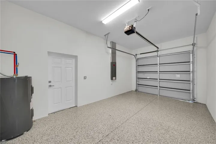 Garage with water heater, a garage door opener, and electric panel