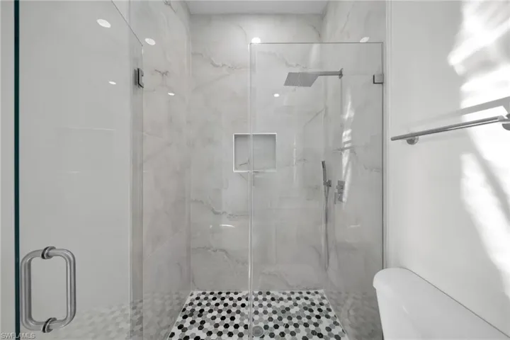 Full bathroom featuring a marble finish shower and toilet