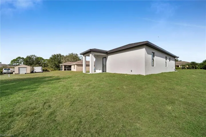 View of property exterior featuring a lawn, stucco siding, and a patio area