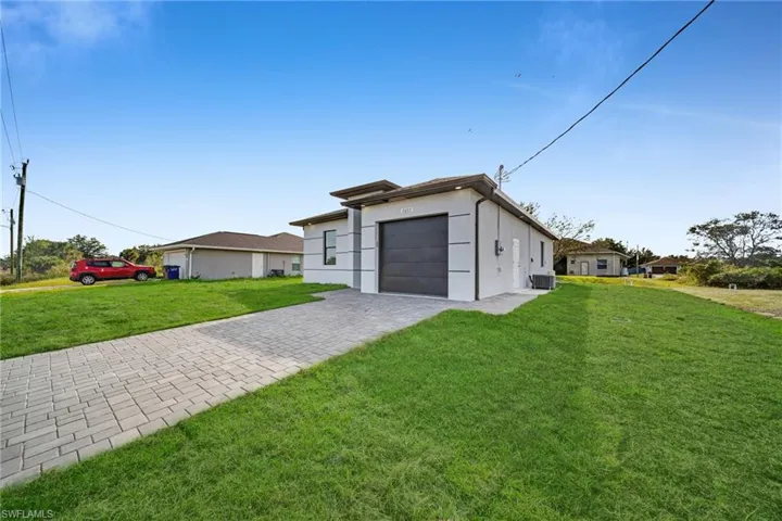 View of front of home with decorative driveway, a front yard, stucco siding, and an attached garage