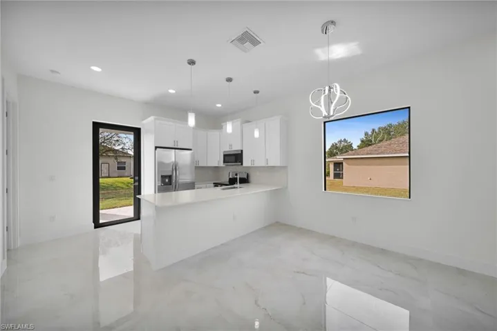Kitchen with white cabinets, stainless steel appliances, decorative light fixtures, healthy amount of natural light, and recessed lighting