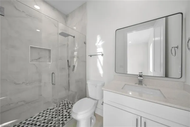 Bathroom featuring vanity and a marble finish shower