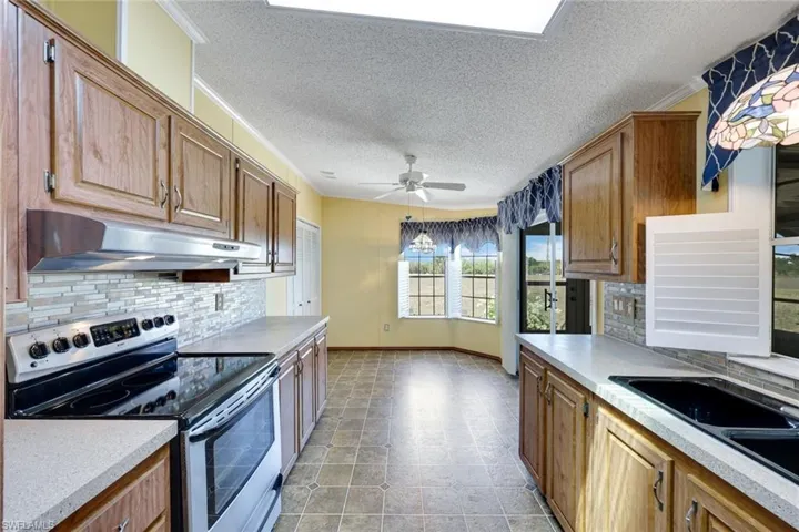 Beautifully upgraded Kitchen features stainless steel appliances, glass backsplash, solid-surface counters, ceiling fan, and raised-panel wood cabinets.
