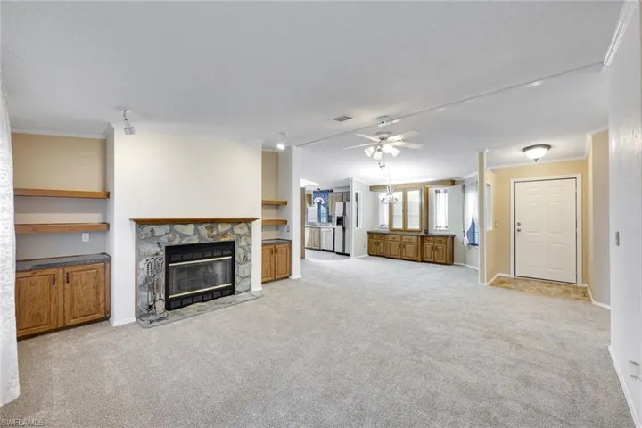 Expansive Great Room (with view to Kitchen) features built-in cabinetry, brand new neutral carpet, and a wood burning fireplace.