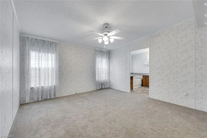 Primary Bedroom with window coverings, neutral carpet, ceiling fan, and ensuite.