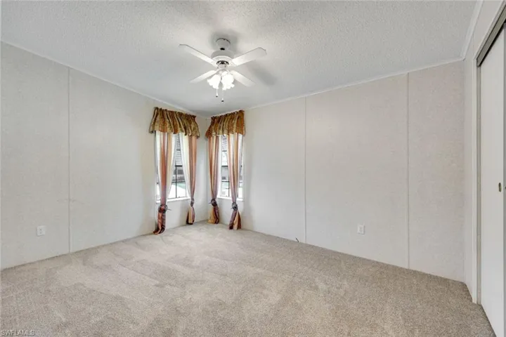 Bedroom #2 with neutral carpet, ceiling fan, and plenty of closet space.