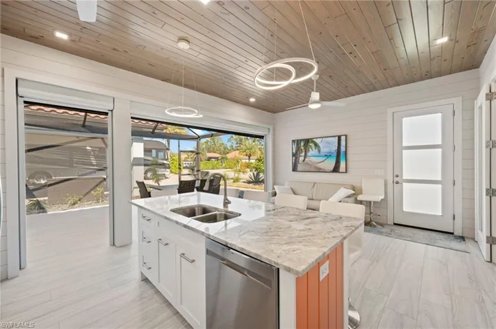 Kitchen with light stone counters, healthy amount of natural light, a sunroom, dishwasher, and wood ceiling