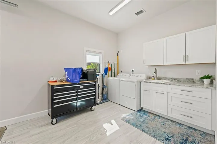 Laundry area featuring light wood-type flooring, washer and dryer, and cabinet space