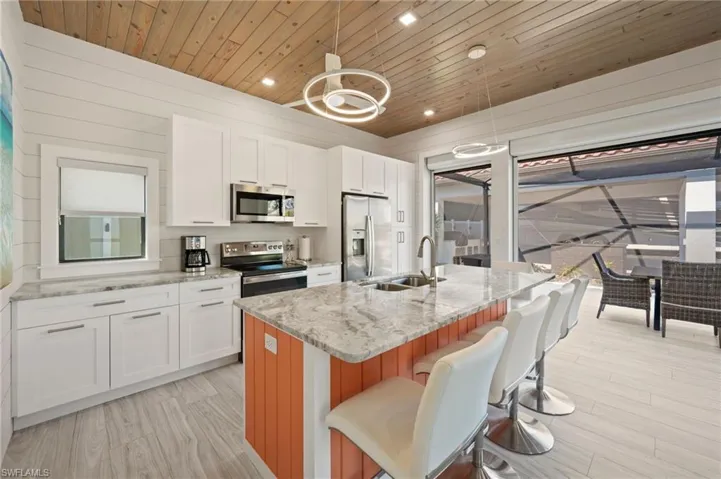 Kitchen featuring white cabinetry, wooden ceiling, appliances with stainless steel finishes, light stone counters, and recessed lighting