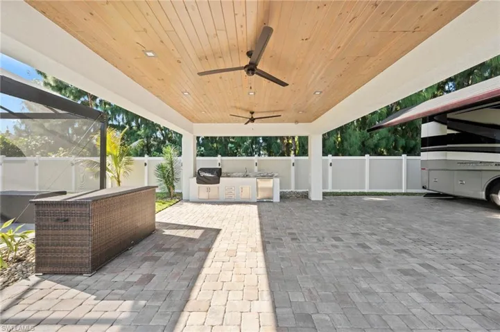 Fenced backyard featuring a ceiling fan, area for grilling, a patio area, and glass enclosure