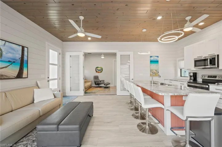 Living room with ceiling fan, wood walls, wooden ceiling, and light wood-style flooring
