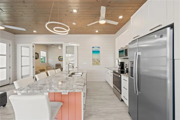 Kitchen with a breakfast bar area, appliances with stainless steel finishes, recessed lighting, wooden walls, and white cabinets