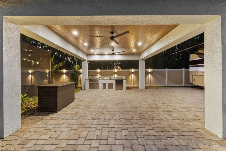 Fenced backyard featuring an outdoor kitchen, a ceiling fan, and a patio area
