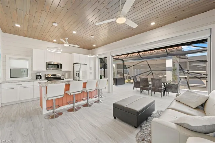 Living room with a sunroom, recessed lighting, plenty of natural light, a ceiling fan, and light wood-type flooring