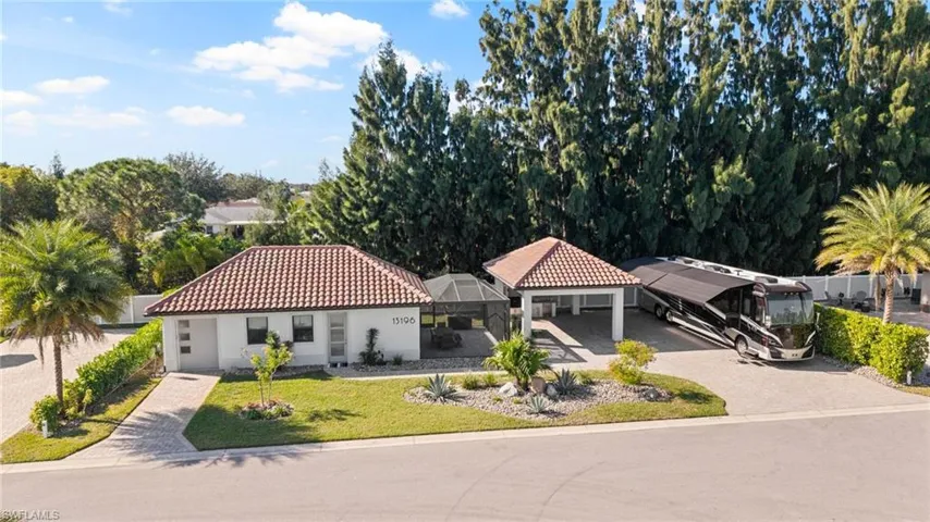 View of front of property featuring a tiled roof, glass enclosure, stucco siding, and driveway