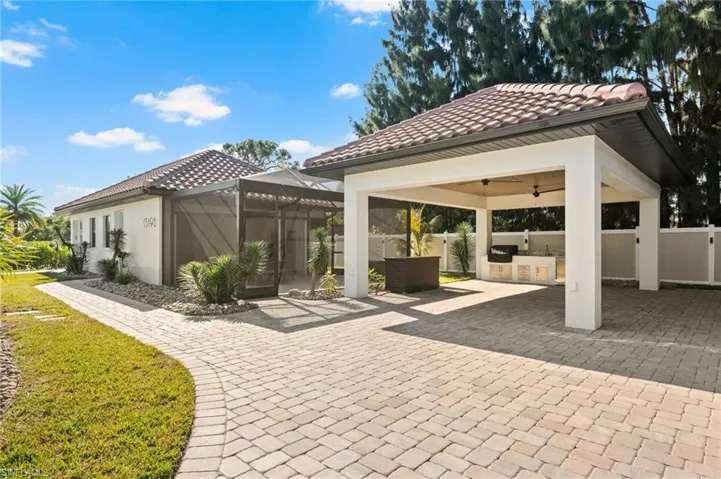 View of patio with an outdoor kitchen, ceiling fan, and a lanai