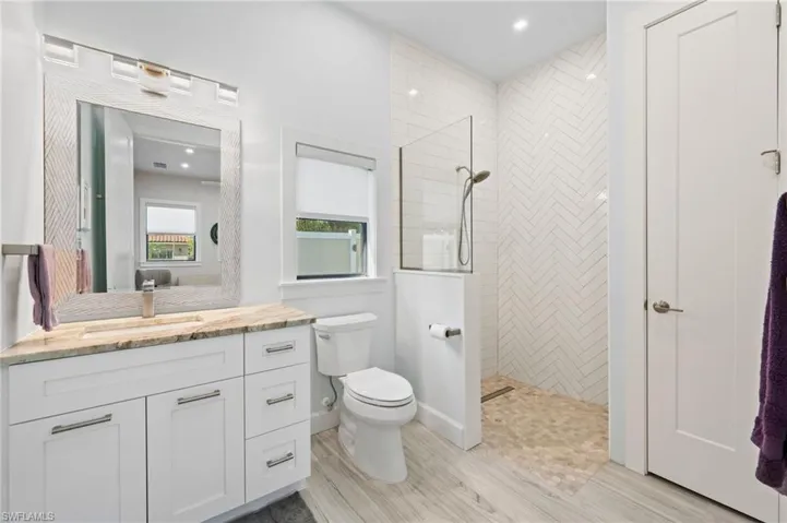Bathroom with walk in shower, vanity, recessed lighting, and light wood finished floors