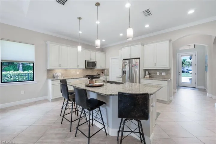 Kitchen island large enough to sit 4, stainless steel appliances, and plenty of natural light