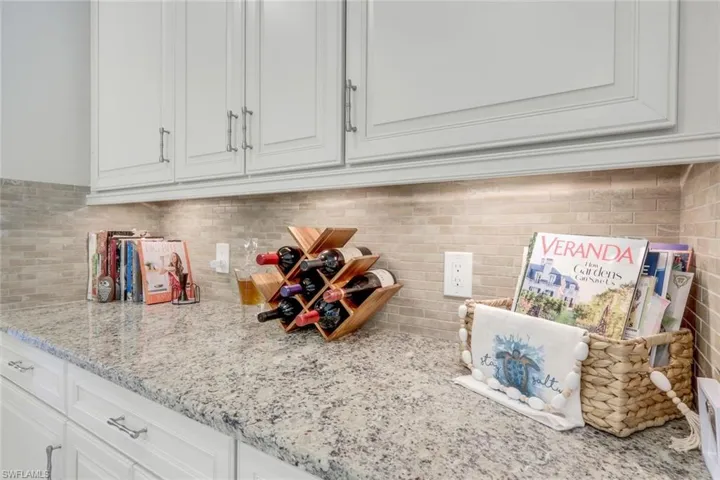 Kitchen featuring light stone countertops, white cabinets, and lovely backsplash