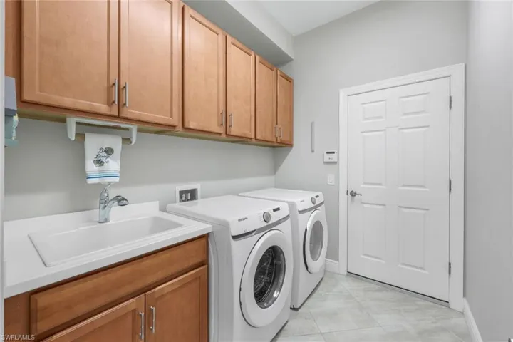 Laundry room featuring separate washer and dryer, cabinets, and sink