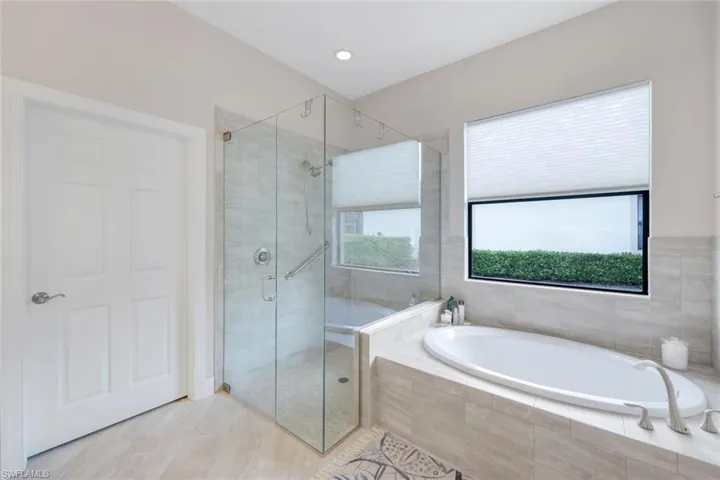 Primary bathroom with tile patterned flooring, separate shower and tub and large walk-in closet