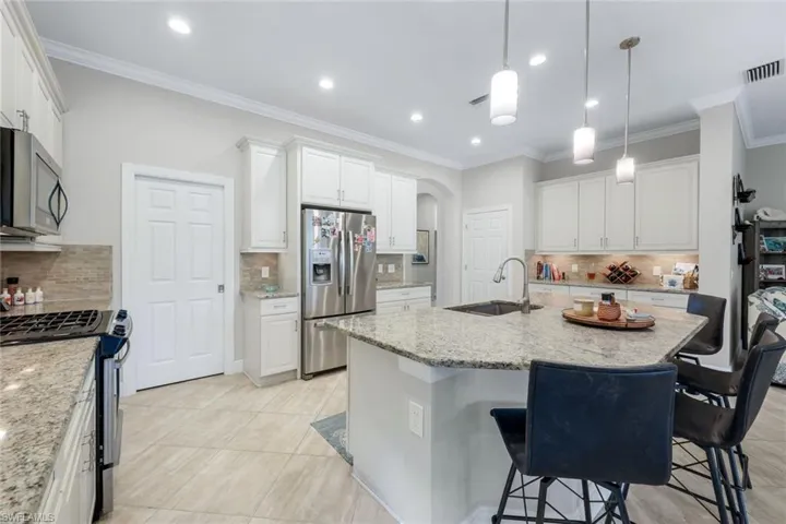 Kitchen bar, decorative backsplash, and a center island with sink