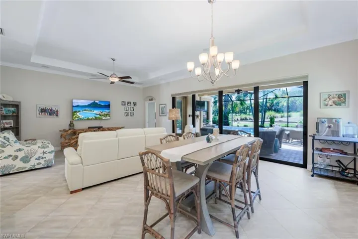 Dining room with ceiling fan, chandelier, a raised ceiling, and light tile patterned floors