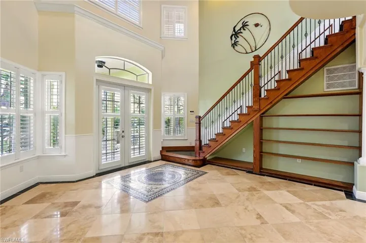 Entryway with french doors, stairway, a high ceiling, and baseboards