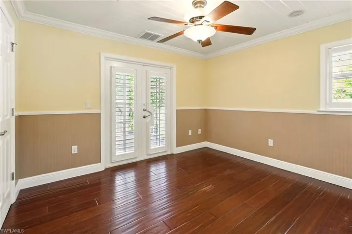 Spare room with wainscoting, wood-type flooring, ceiling fan, ornamental molding, and wooden walls