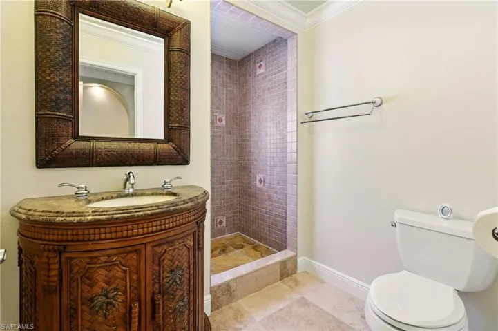 Full bath featuring toilet, ornamental molding, vanity, a shower stall, and baseboards