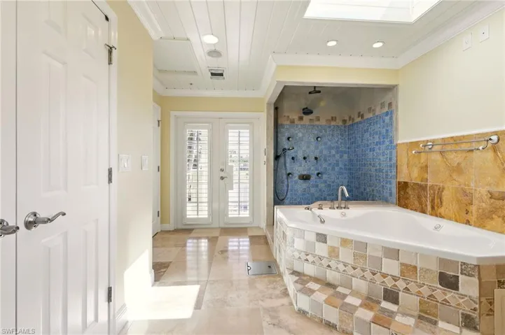 Full bathroom featuring ornamental molding, tiled bath, french doors, a tile shower, and recessed lighting